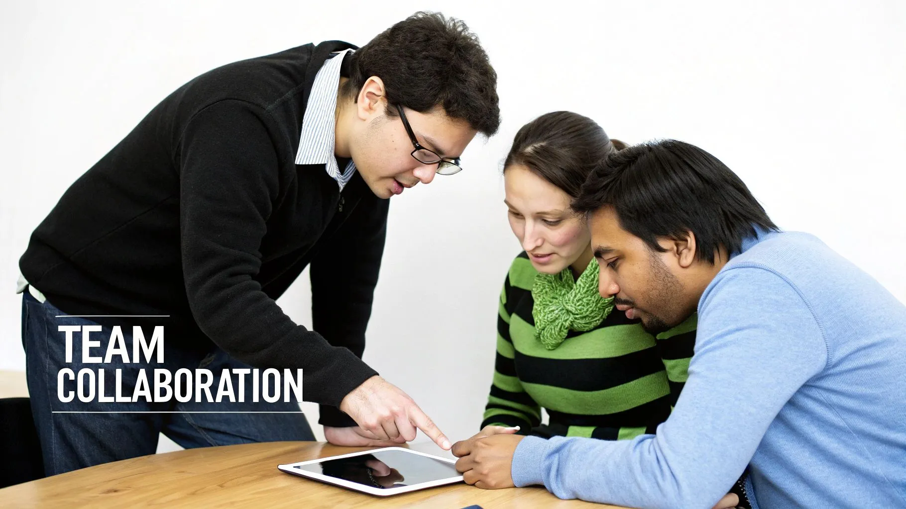 A diverse team collaborates around a digital tablet, discussing project details and pointing at the screen.